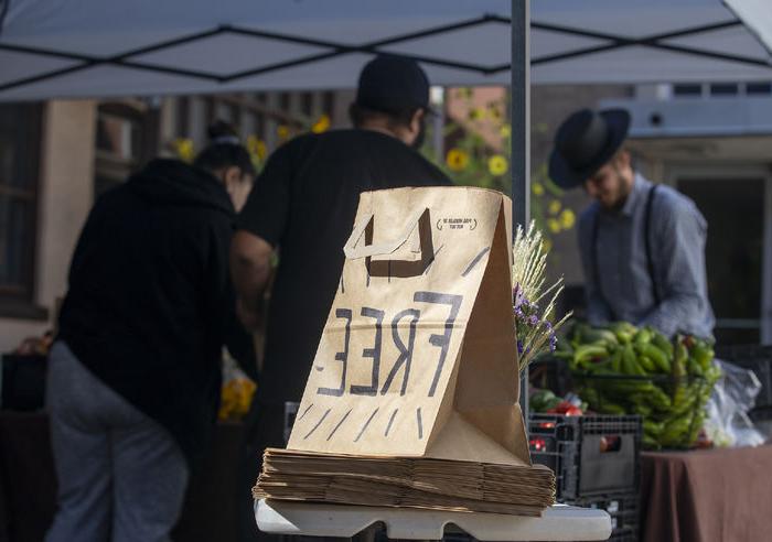 A paper bag labeled "Free Food" sits in front of a stall of fresh produce