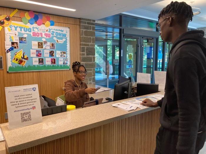 Student working front desk at Lions Gate